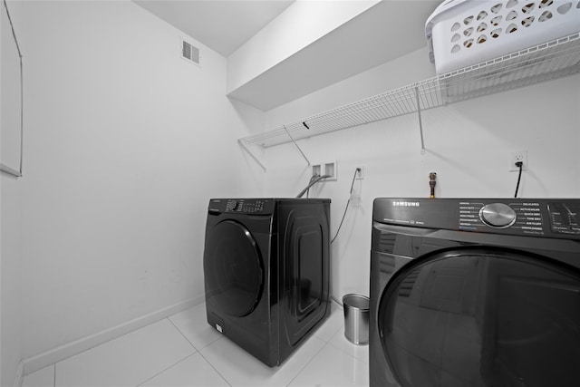 clothes washing area with washer and clothes dryer and light tile patterned floors