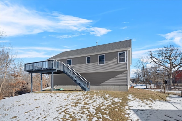 snow covered rear of property with a wooden deck