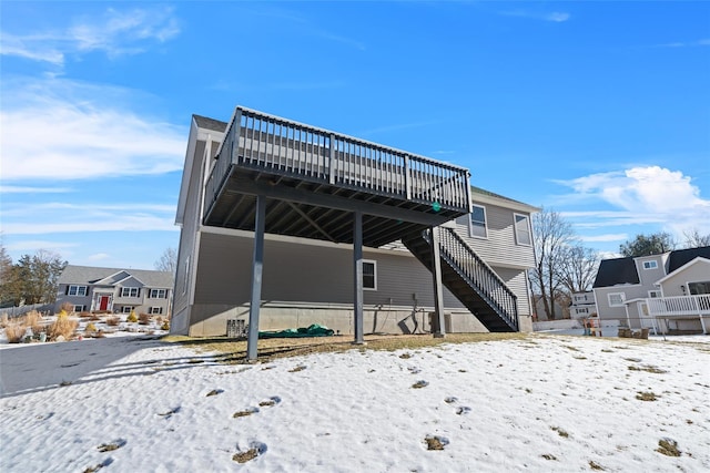 snow covered back of property with a deck