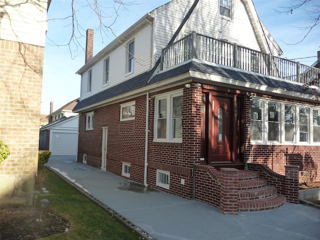 view of home's exterior featuring a garage, an outdoor structure, and a balcony