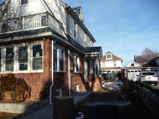 view of side of property with a garage, a balcony, and an outdoor structure