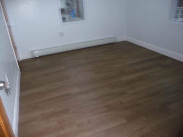 spare room with dark wood-type flooring and a baseboard heating unit