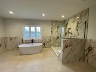 bathroom featuring plus walk in shower and tile walls