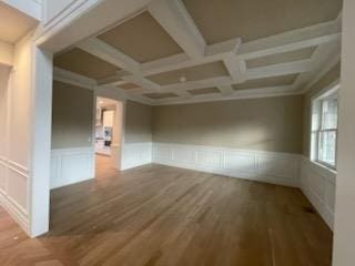 empty room featuring coffered ceiling, hardwood / wood-style flooring, and beam ceiling