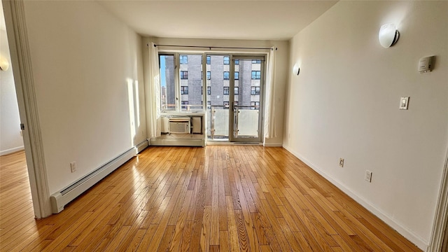 empty room with a baseboard heating unit, light hardwood / wood-style flooring, and a wall mounted AC