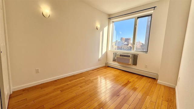 unfurnished room featuring a wall mounted air conditioner, baseboard heating, and light hardwood / wood-style flooring