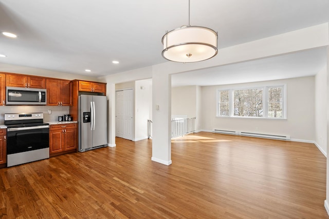 kitchen with stainless steel appliances, light hardwood / wood-style floors, hanging light fixtures, and a baseboard heating unit