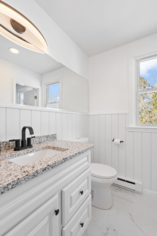 bathroom featuring vanity, a baseboard heating unit, and toilet