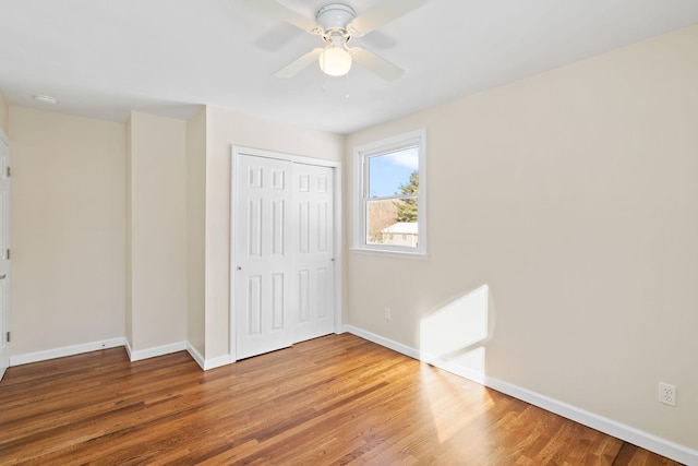 unfurnished bedroom featuring hardwood / wood-style flooring, a closet, and ceiling fan