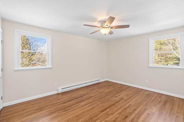 empty room featuring hardwood / wood-style flooring, ceiling fan, a wealth of natural light, and baseboard heating