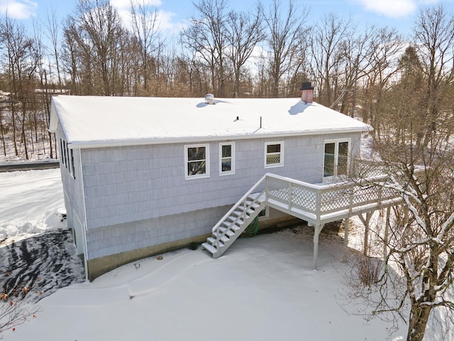 snow covered back of property with a deck