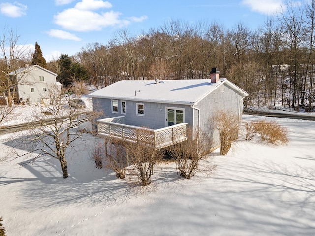 snow covered back of property with a wooden deck