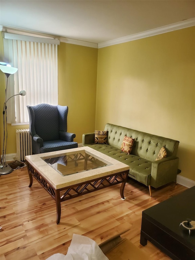 living room with radiator, baseboards, crown molding, and light wood finished floors