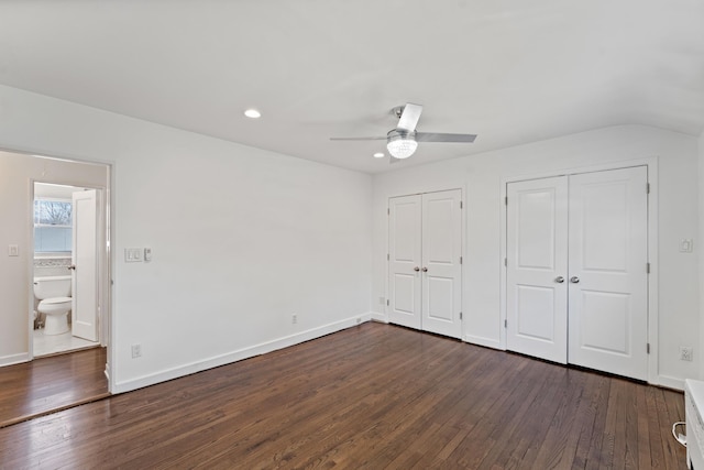 unfurnished bedroom with ceiling fan, lofted ceiling, dark hardwood / wood-style flooring, and two closets