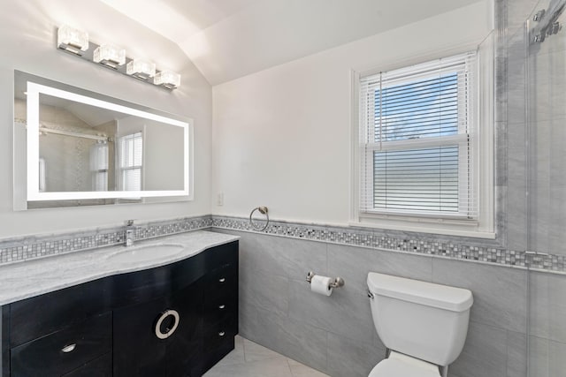 bathroom featuring vaulted ceiling, a shower, tile walls, vanity, and toilet