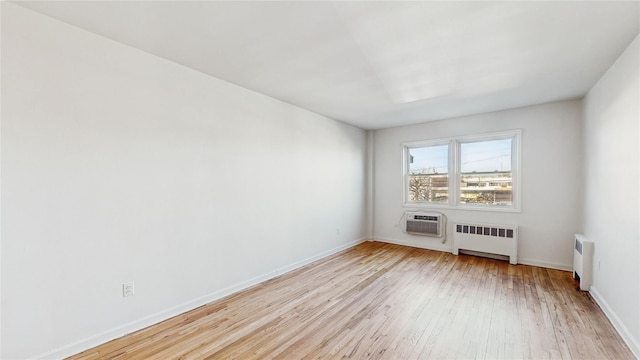 empty room with radiator, a wall unit AC, and light hardwood / wood-style floors