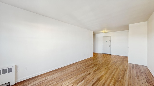 spare room with radiator heating unit and light wood-type flooring