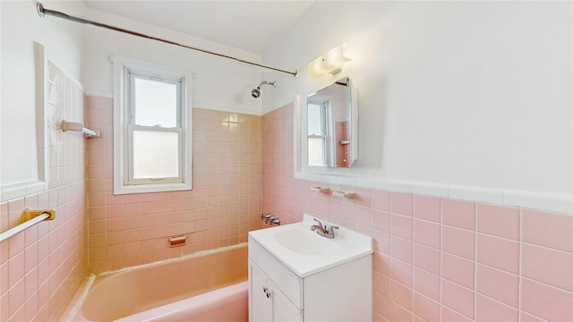 bathroom featuring tiled shower / bath combo, vanity, and tile walls