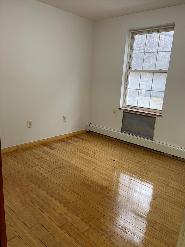 spare room with a baseboard radiator and light hardwood / wood-style flooring