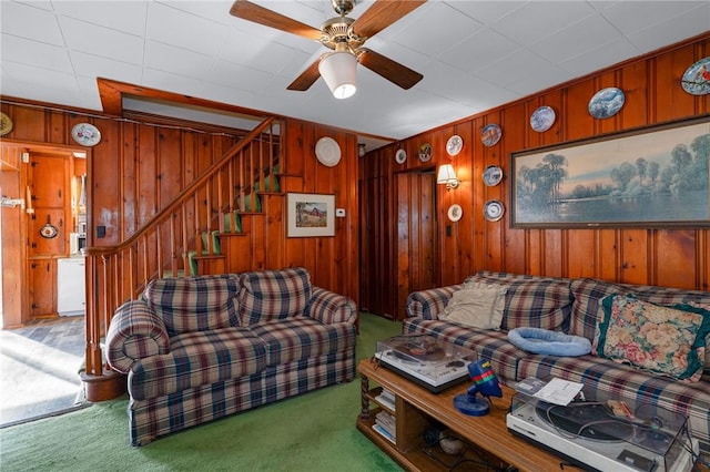 living room featuring ceiling fan, wooden walls, and carpet floors