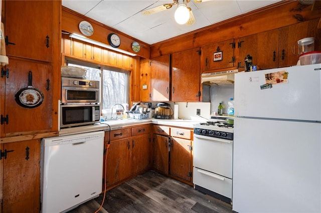 kitchen with wooden walls, white appliances, dark hardwood / wood-style flooring, and sink