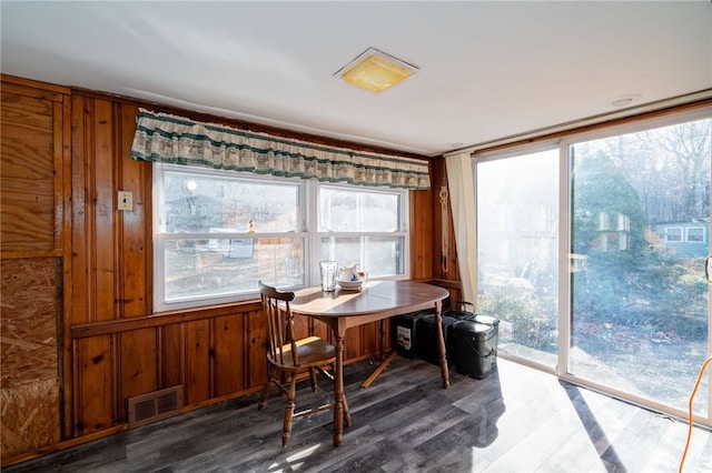 dining area featuring wood-type flooring, plenty of natural light, and wooden walls