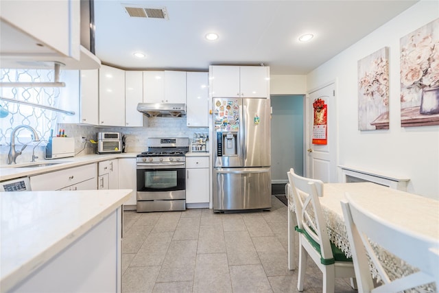 kitchen featuring sink, light tile patterned floors, appliances with stainless steel finishes, tasteful backsplash, and white cabinets