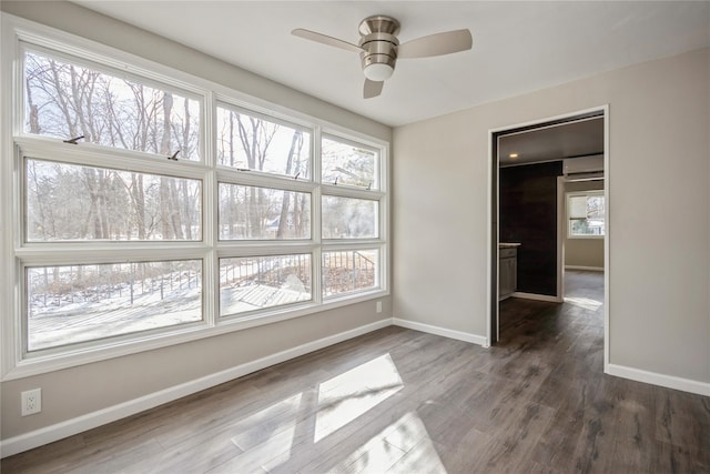 empty room with dark hardwood / wood-style flooring, ceiling fan, and a healthy amount of sunlight