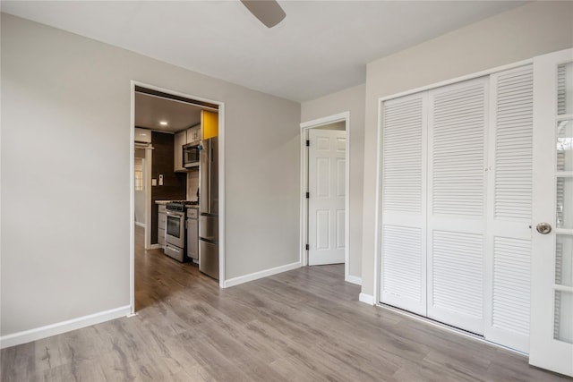 unfurnished bedroom featuring ceiling fan, stainless steel fridge, light hardwood / wood-style floors, and a closet