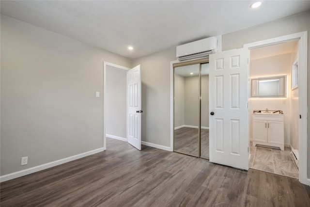 unfurnished bedroom with dark wood-type flooring, a wall mounted air conditioner, and a closet