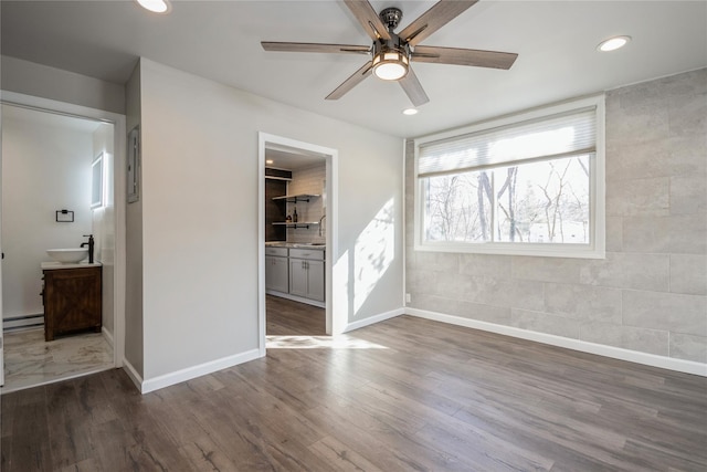 unfurnished bedroom with a baseboard heating unit, sink, dark hardwood / wood-style flooring, and ensuite bath