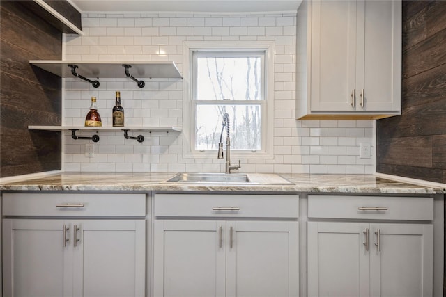 kitchen featuring light stone counters, sink, and decorative backsplash