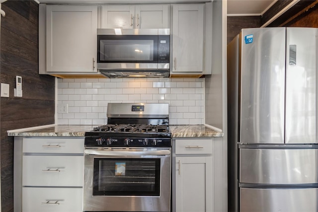 kitchen featuring stainless steel appliances, tasteful backsplash, gray cabinetry, and light stone counters