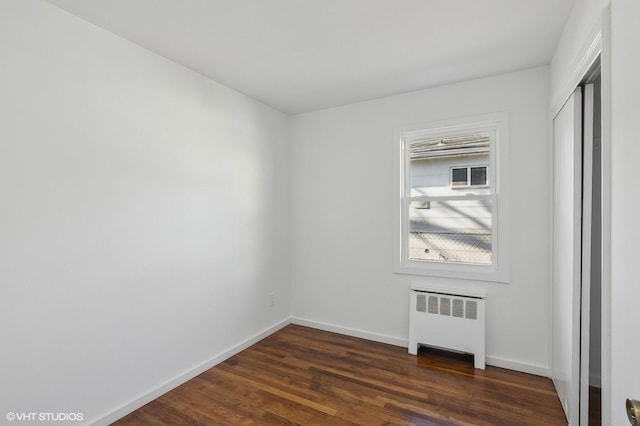 unfurnished room featuring dark wood-type flooring and radiator heating unit