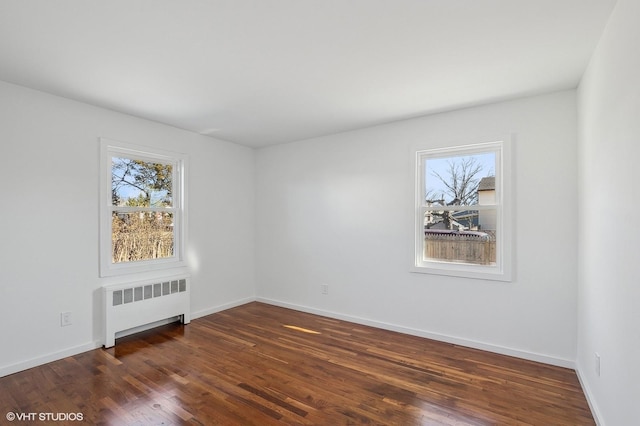 spare room with dark hardwood / wood-style flooring and radiator