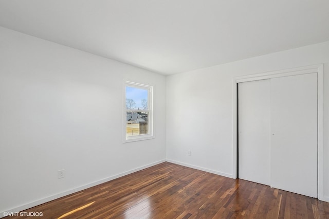 unfurnished bedroom with dark wood-type flooring and a closet