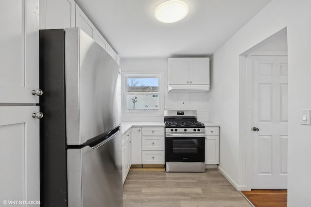 kitchen with light countertops, light wood-style flooring, decorative backsplash, appliances with stainless steel finishes, and white cabinets