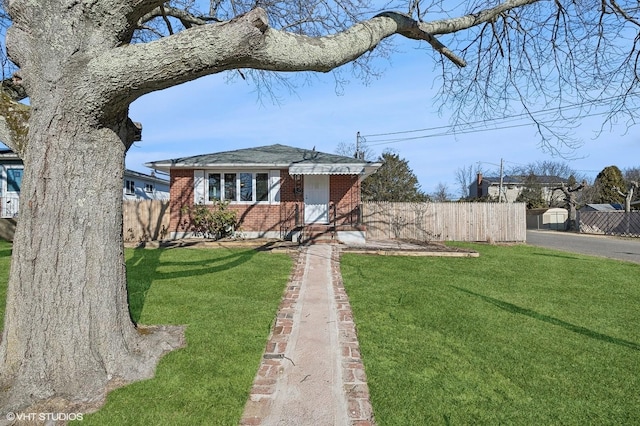 view of front of property with fence, a front lawn, and brick siding