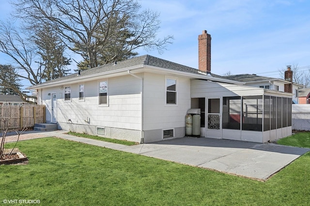 back of house with a sunroom, a chimney, roof with shingles, fence, and a yard