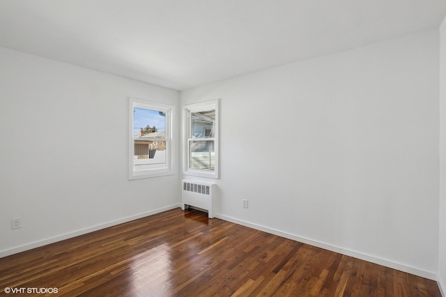 unfurnished room featuring dark wood-type flooring, radiator, and baseboards