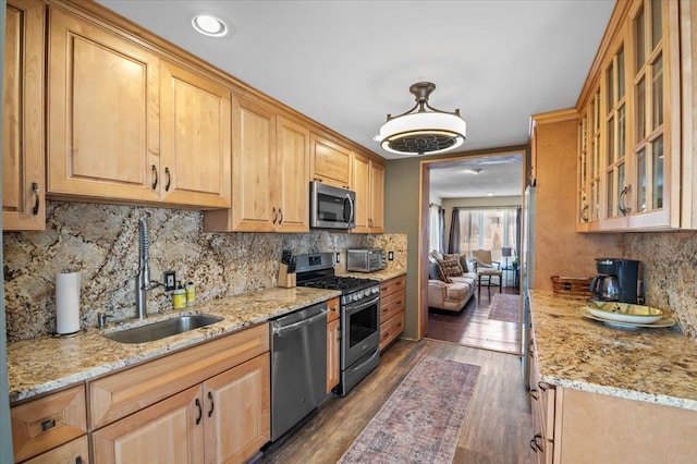 kitchen with pendant lighting, sink, stainless steel appliances, light stone countertops, and dark hardwood / wood-style flooring