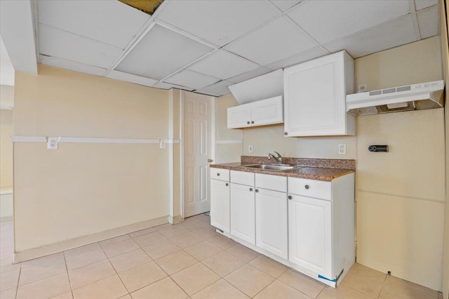 kitchen with sink, a drop ceiling, white cabinets, and light tile patterned floors