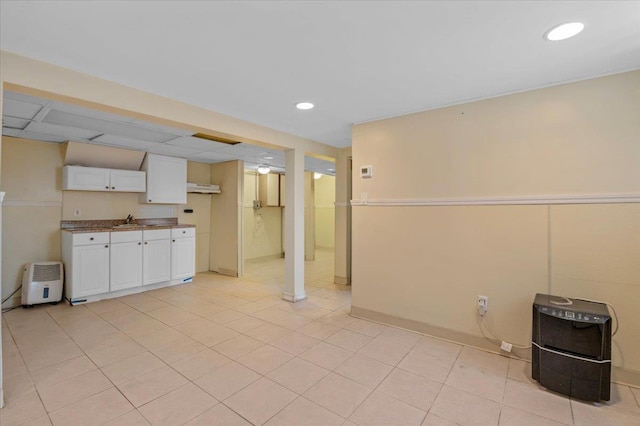 interior space with light tile patterned floors, sink, and white cabinets