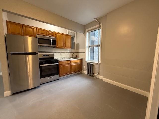 kitchen with tasteful backsplash, radiator, sink, and appliances with stainless steel finishes