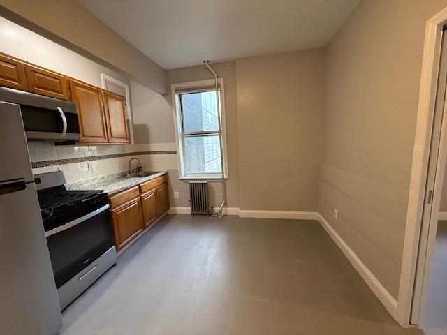 kitchen with backsplash, radiator heating unit, stainless steel appliances, and sink