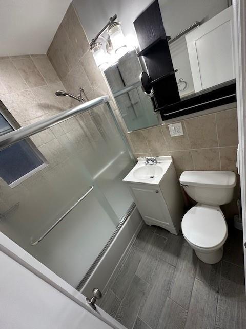 bathroom featuring vanity, tasteful backsplash, tile walls, and toilet