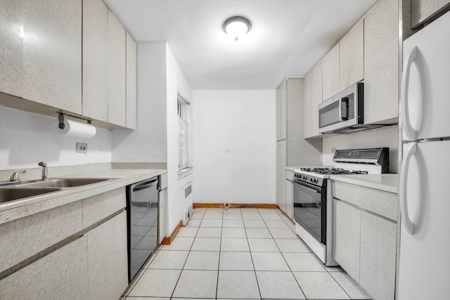 kitchen featuring freestanding refrigerator, a sink, gas range oven, dishwasher, and stainless steel microwave