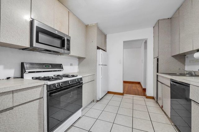 kitchen featuring light tile patterned floors, white appliances, light countertops, and a sink