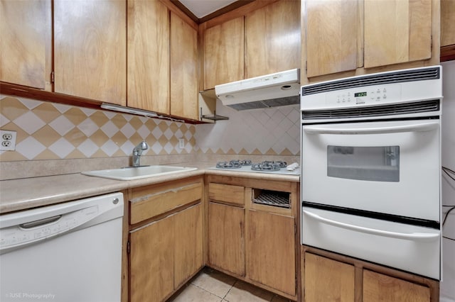 kitchen featuring light tile patterned flooring, white appliances, sink, and decorative backsplash