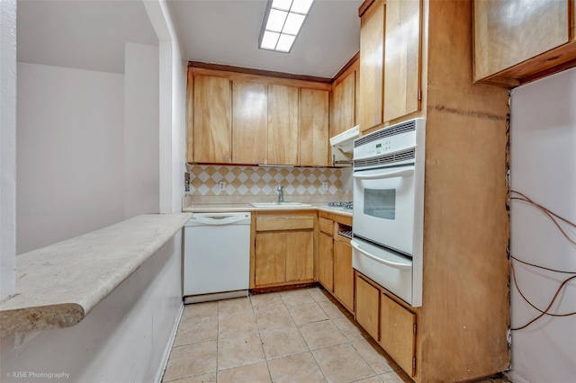 kitchen with sink, white appliances, light tile patterned floors, tasteful backsplash, and kitchen peninsula